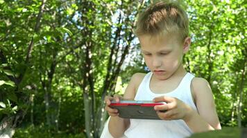 boy who is completely absorbed in playing on his cell phone misses the opportunity to interact with the environment, which can lead to harmful gadget addiction at an early age video