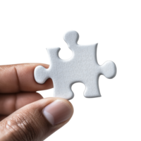 A close-up of a hand holding a single white puzzle piece. The background is isolated and plain, highlighting the texture and shape of the piece. png