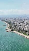 Coastline showing mersin city extending along turquoise water. Buildings and palm trees are visible. Mountains are seen in the distance video