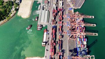 Aerial views showcase a container ship docked for cargo loading by three cranes, while nearby tugboats assist with maneuvering operations video