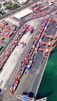 Cargo container terminal with gantry cranes loading unloading containers to cargo ships at sunset. Global logistics aerial view video