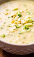 A bowl of creamy soup with broccoli and cheese photo