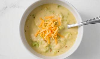 A bowl of broccoli cheese soup with a spoon photo