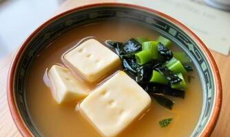 A bowl of soup with tofu and green vegetables photo