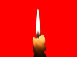 A single burning candle flame or light glowing on a small spiral white candle isolated on red background with clipping path photo
