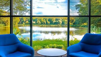 Two blue chairs and a table in front of a large window with a view of a lake video