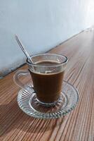 Coffee milk is stirred in a glass using a spoon on the table photo