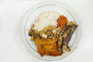 Rice mixed with fried fish and tempeh vegetables on a white plate, on the table photo