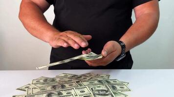 A person is maneuvering bills on a table, smoothly sliding cash across a surface while a pile of money sits in front. The atmosphere suggests a transaction is taking place video