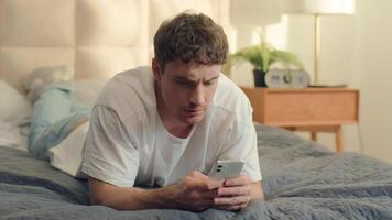 Serious Caucasian man bed using mobile phone smartphone guy male technology pensive problem frown error rejection fail broken gadget spam connection notification stressful worry wrong trouble banking video