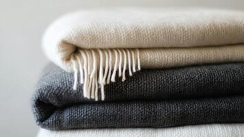 Stack of soft, cozy blankets in neutral colors resting on a light surface for home decor photo