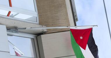 The flag of Jordan is waving in the wind against the backdrop of a building. The Jordanian Embassy. video
