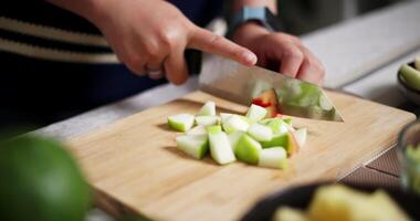 Handheld selective focus shot, Young Asian woman using knife to cut fruit on cutting board to prepare for eating on table at home. Lifestyle at home video