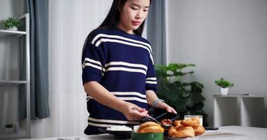 Handheld shot, Young Asian woman is scooping food out of plastic container into bowls to prepare for lunch on the table at home. Home lifestyle. video