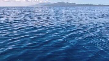 A boat is sailing in the ocean with a mountain in the background video