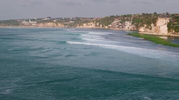 Drone view of coastline with cliffs and ocean with surfing waves in Bali video