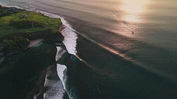 Swell lines waves in ocean with evening sunlight in Bali, drone view video