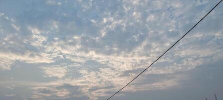 A view of the sky with clouds and a power line photo