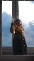 A child is standing in front of a window with water on it video