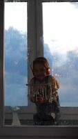 vertical Little girl in headphones washes a window with a glass scraper video