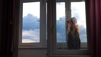 A person standing in front of a window with rain on it video