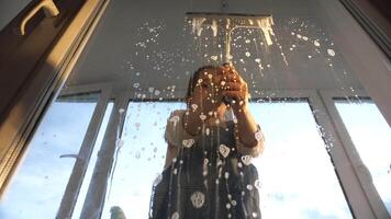 A person standing in front of a window with water running down the glass video