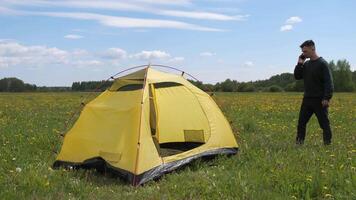 a man on a hike near a tent tries to find a mobile connection, cellular network video