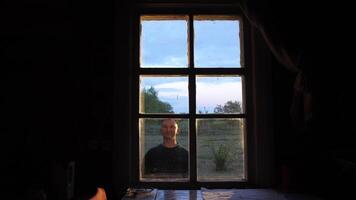 early guest concept. man stands in front of window and waves hand in greeting video