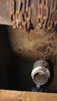 vertical process of raising water from a village well with a bucket on a chain video