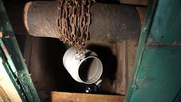 Bucket on a chain for extracting water from a well. video