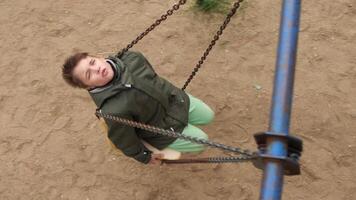 High angle shot of a kid riding on a swing on a rusty chain in slow motion video