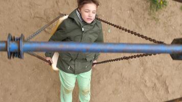 High angle shot of a kid riding on a swing on a rusty chain in slow motion video
