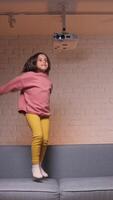 vertical happy little girl jumping for joy on the sofa video