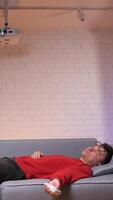 vertical man fell asleep on the sofa while watching a boring movie video