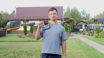 Gardener holding string trimmer on shoulder posing in garden video