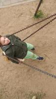 vertical High angle shot of a kid riding on a swing on a rusty chain video