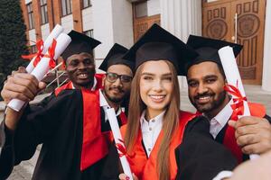 Diverse Group of Happy Graduates Celebrating With Diplomas Outside School Building photo