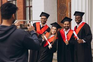 Group of Happy Graduates Celebrating Outside University with Diplomas and Taking Photos