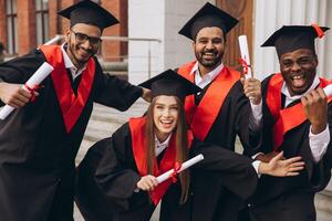 Group of Happy Graduates Celebrating with Diplomas in Hand on Graduation Day photo