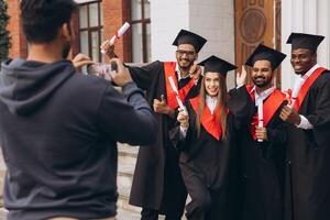 Group of Happy Graduates Celebrating Outside University with Diplomas and Taking Photos