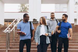 Diverse Group of Students Walking on Campus Steps and Smiling With Books and Backpacks photo