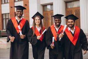 Joyful Group of Graduates Celebrating Their Academic Success in Caps and Gowns Outside the University photo