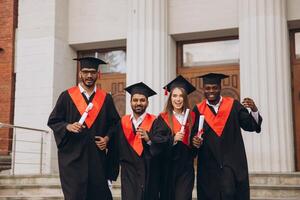 Group of Happy Graduates Celebrating Success Holding Diplomas Outside University Building photo