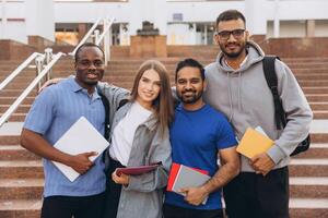 Diverse Group of Happy University Students Posing Together on Campus Steps Holding Notebooks photo