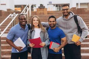 Diverse Group of Happy University Students Posing Together on Campus Steps Holding Notebooks photo