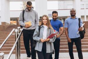 Diverse Group of Smiling College Students Walking on Campus Stairs with Backpacks and Books photo