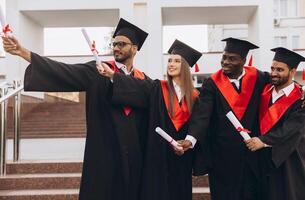 Diverse Group of Happy Graduates Celebrating Achievement with Diplomas in Academic Caps and Gowns Outdoors photo