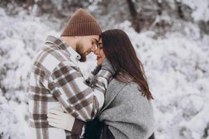 A young happy and loving couple walking in a winter snowy forest in the mountains photo
