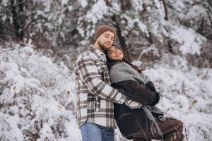 A young happy and loving couple walking in a snowy forest in the mountains photo