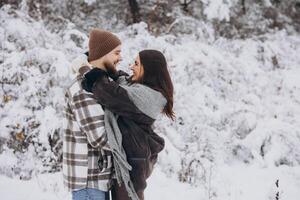 Portrait of a young happy and loving couple having fun in a snowy forest photo